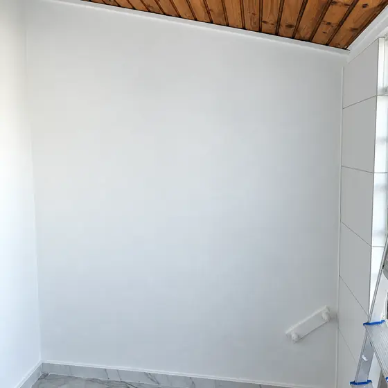 Parede pintada de branco em ambiente com forro de madeira
