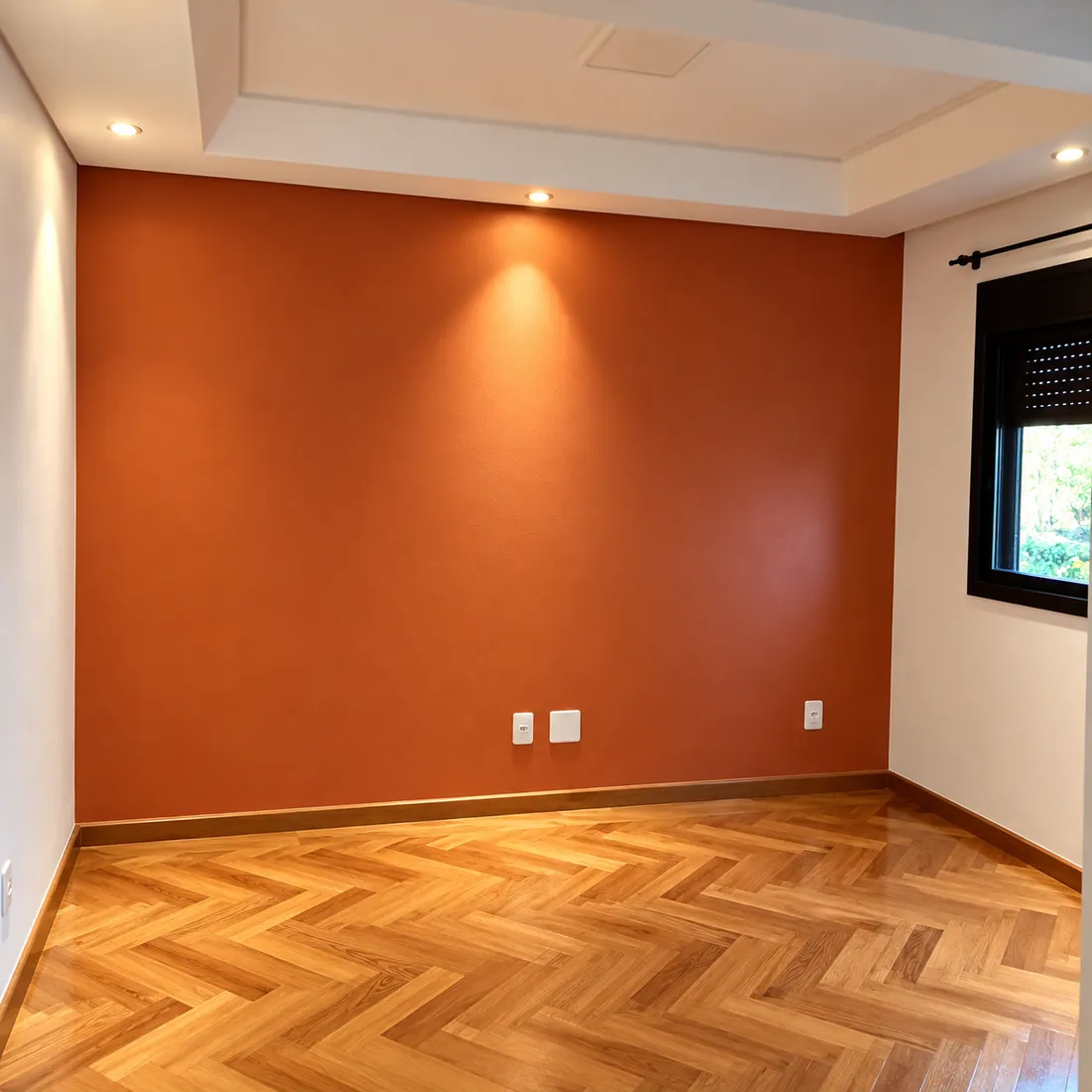 Quarto com parede pintada em terracota, spots no teto e piso de madeira
