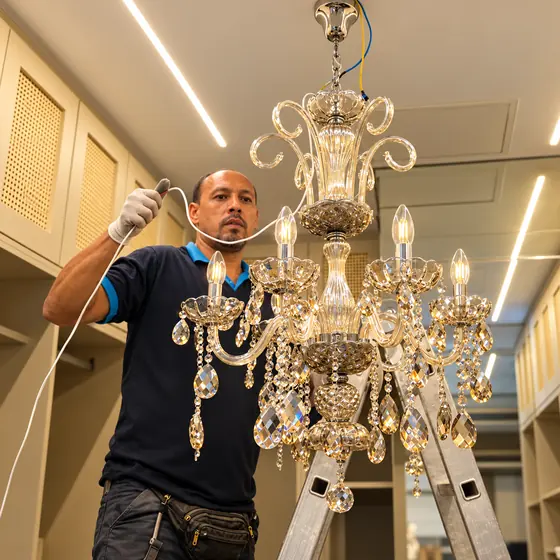 William ligando um lustre de cristal no alto da escada